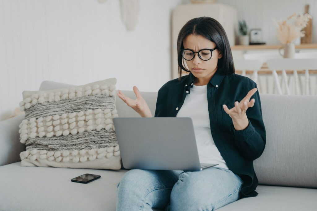 Angry woman struggles with laptop, forgets password. Unhappy, reads bad news, weak wifi