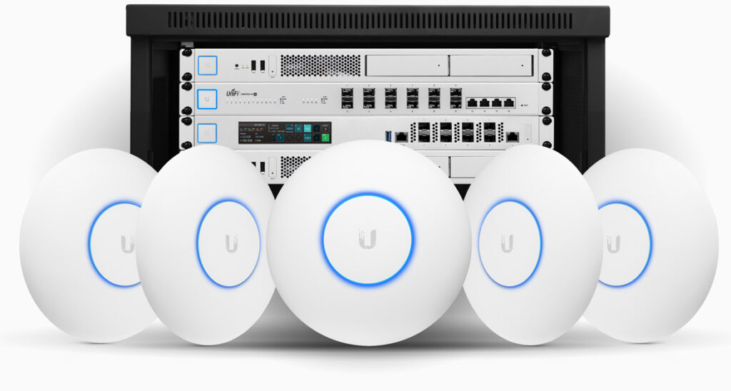 Five white round Wi‑Fi access points with blue glow rings in front of a server rack.