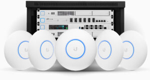 Five white round Wi‑Fi access points with blue glow rings in front of a server rack.